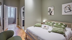 A bedroom with a bed, green pillows, a nightstand, and artwork on the wall. - Sublim Apartment Arc de Triomphe/ Trocadero (Paris)