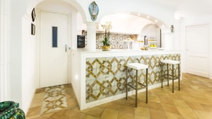 A kitchen with a white countertop, two stools, and a decorative tile backsplash. - Le Anfore exclusive property with private pool (Praiano)