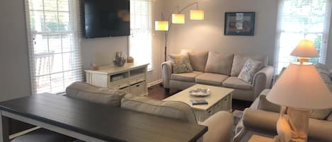 A living room with a sofa, a coffee table, a TV, and a lamp.