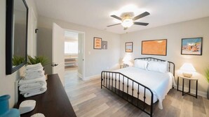 A bedroom with a bed, bedside tables, a ceiling fan, and framed artwork on the walls. - OV Mosaic - Drift Suite (Norfolk)