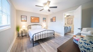 A bedroom with a bed, bedside tables, a ceiling fan, and framed pictures on the wall. - OV Mosaic - Summer Suite (Norfolk)