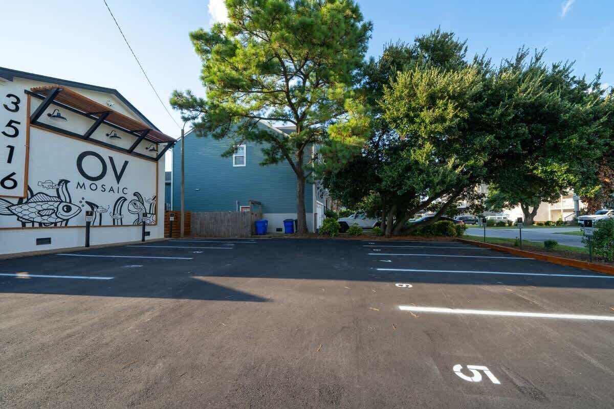Un parking orné d’une fresque murale, avec un arbre et un bâtiment en arrière-plan.