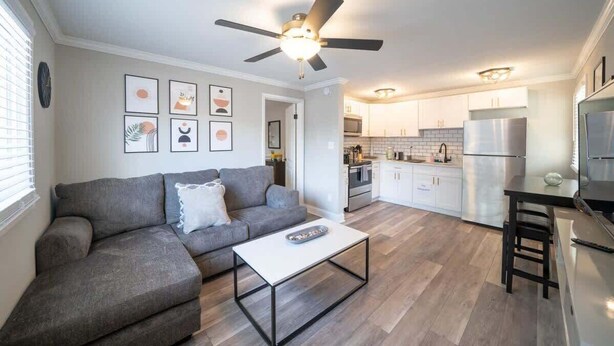 Ein modernes Wohnzimmer mit einem grauen Sofa, einem weißen Couchtisch und einem Deckenventilator.