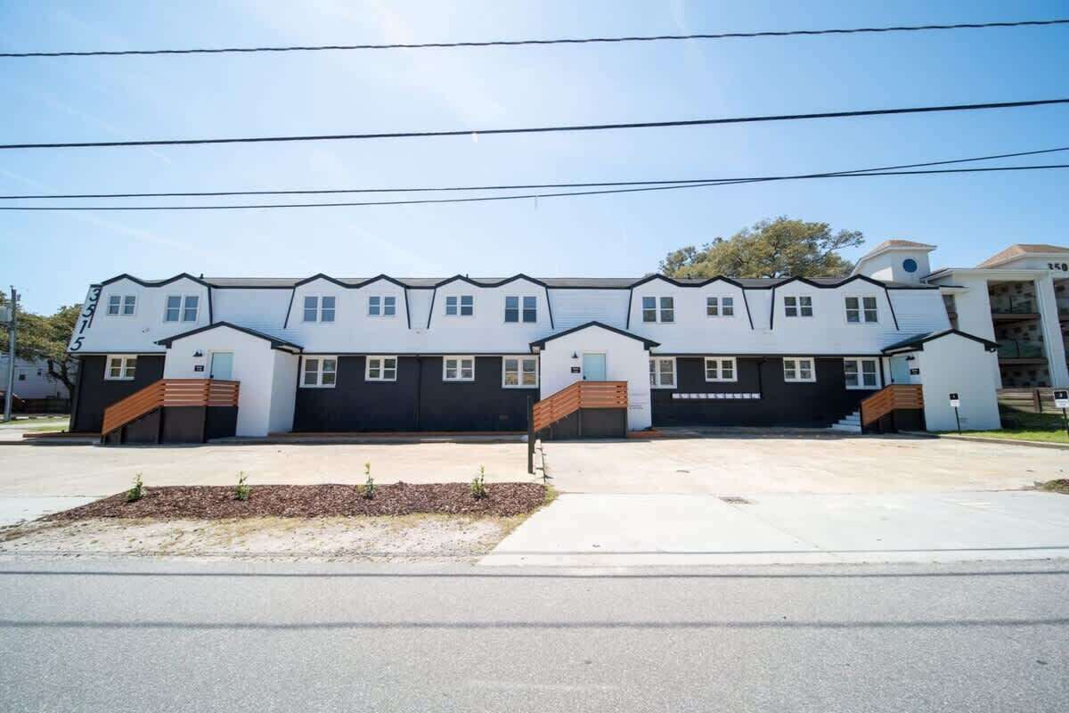 A modern two-story building with a symmetrical facade, multiple garage doors, and a central entrance with a wooden staircase.