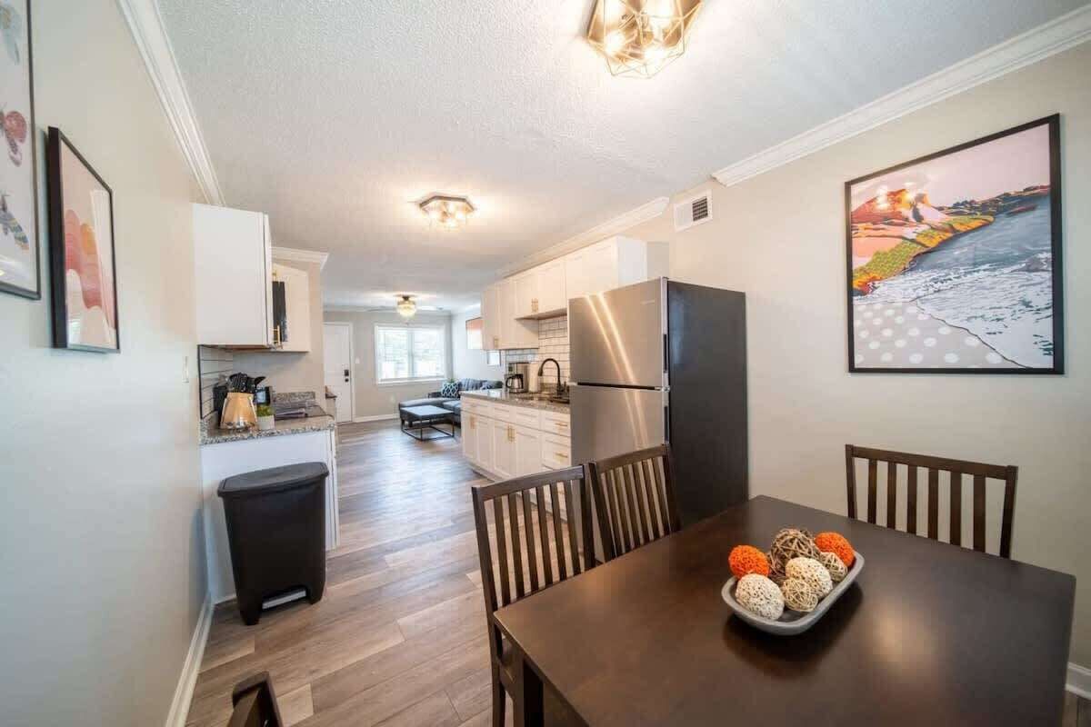 A modern kitchen with white cabinets, stainless steel appliances, and a dining area with a wooden table and chairs.