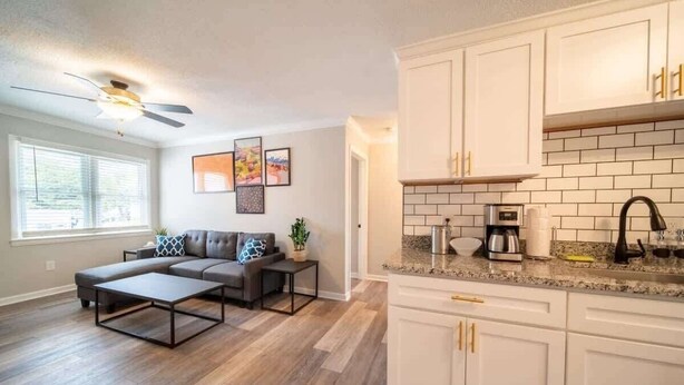A modern kitchen with white cabinets and a granite countertop. - OV Mosaic - River Suite (Norfolk)