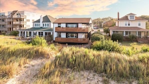 A coastal residential area with modern houses, including a two-story building with a wooden deck and a single-story house with a front porch. - Sojourn Beach Side Paradise Cove Suite (Norfolk)