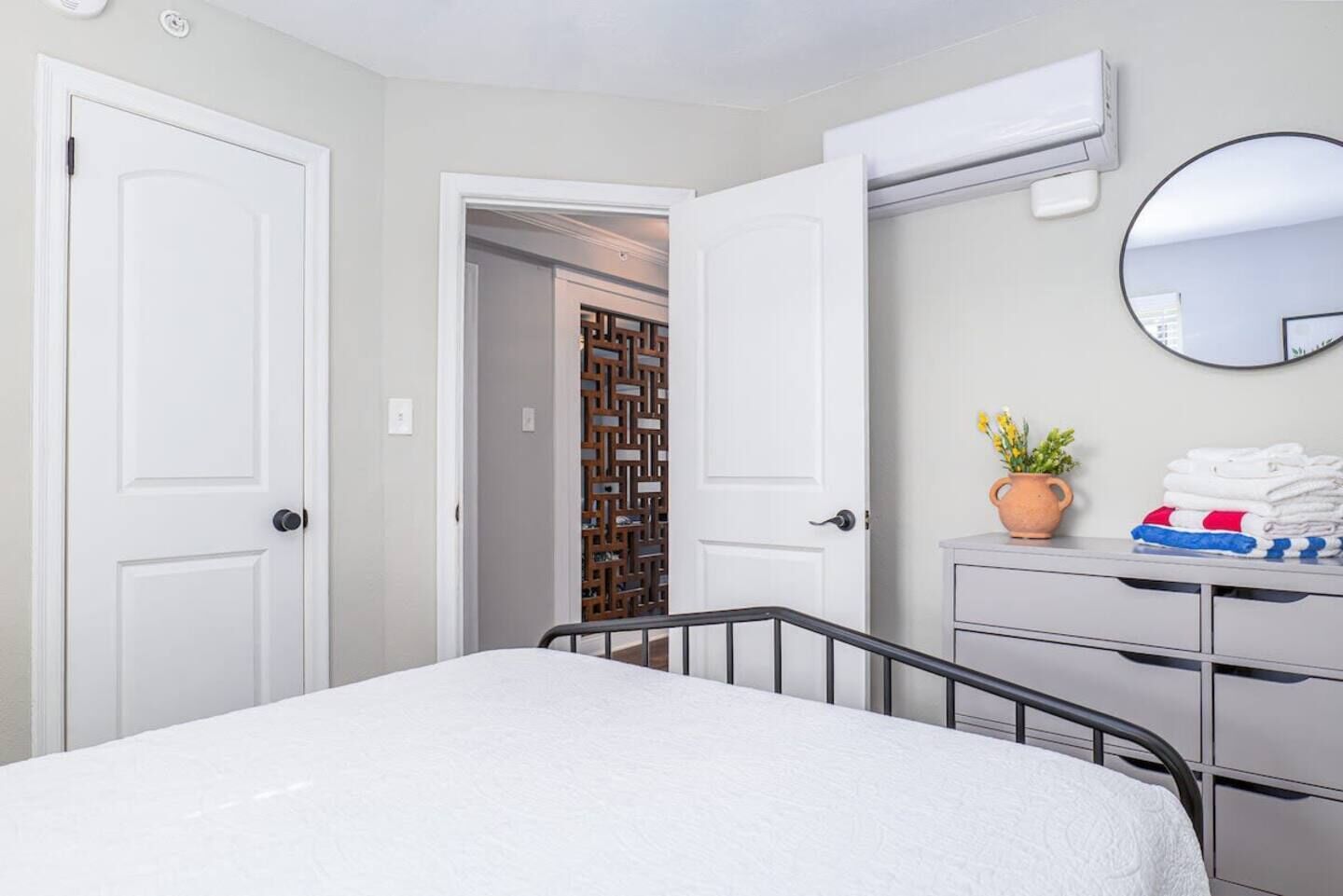 Un dormitorio con cama, cómoda, espejo y unidad de aire acondicionado.