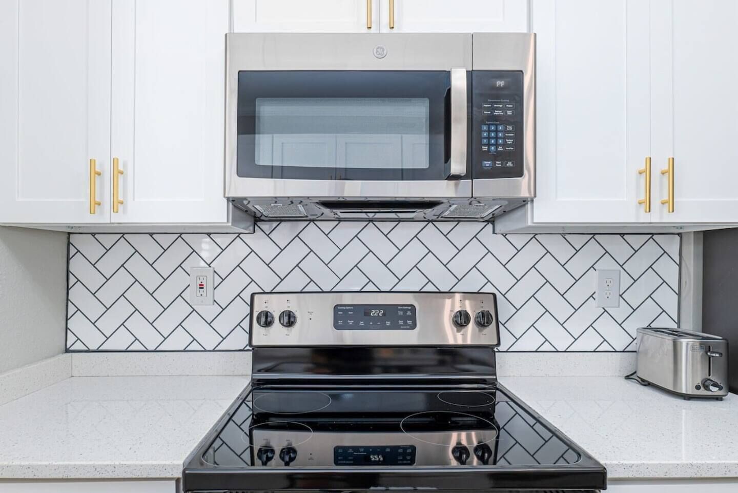 Una cocina con microondas, horno y tostadora de acero inoxidable.