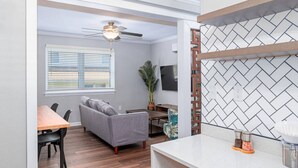 Un salon moderne avec un canapé gris, une table à manger en bois et un ventilateur de plafond.