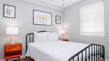 A bedroom with a bed, two bedside tables, a ceiling fan, and a window with blinds.