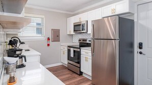 A modern kitchen with white cabinets, stainless steel appliances, and a built-in microwave.