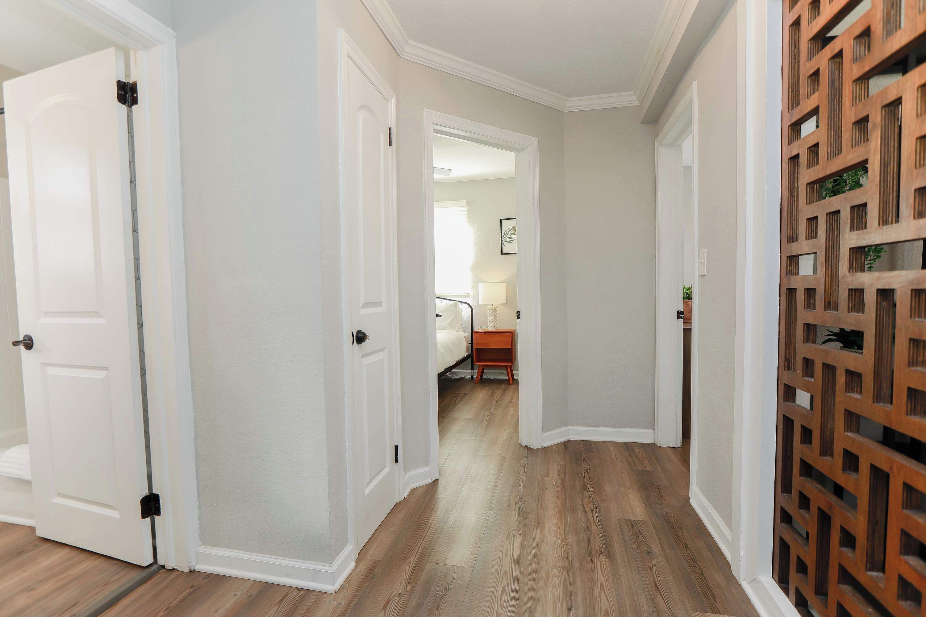 Un pasillo con paredes blancas, piso de madera y un panel decorativo de madera.