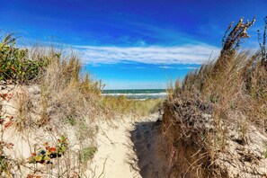 A sandy path leading to the beach with sparse vegetation on either side. - Sojourn 2 BR Beach Side Home with Ocean Views (Norfolk)