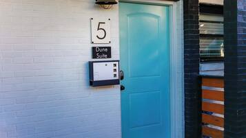 Una puerta turquesa con un letrero con el número 5 arriba y una placa que dice 'Dune Suite' debajo.