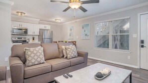 A modern living room with a sofa, coffee table, and kitchen in the background.