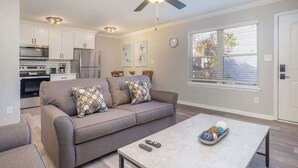 Ein modernes Wohnzimmer mit grauem Sofa, Couchtisch und Deckenventilator.
