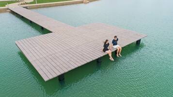 A wooden dock extending over calm water, with two people sitting on it.
