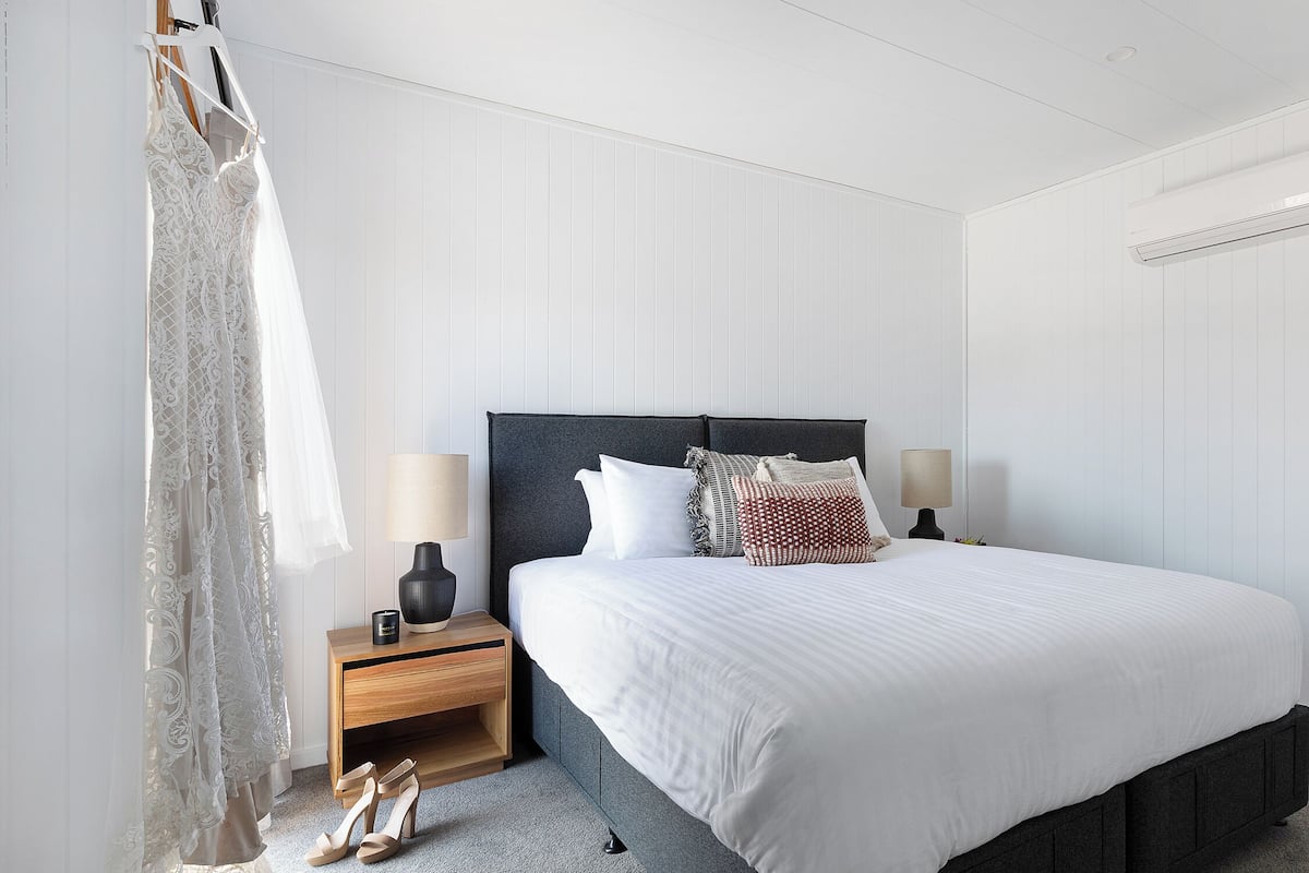 A neatly arranged bedroom with a bed, bedside tables, and a nightstand.