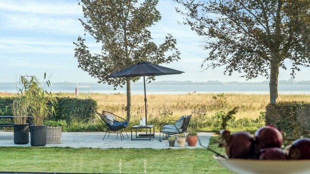 A patio with outdoor furniture, a table, and a bowl of fruit. - 4 Star Holiday Home in Storvorde (Storvorde)