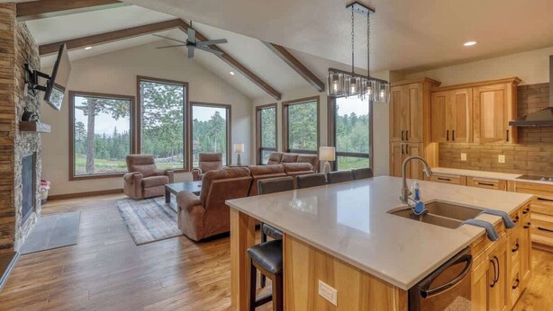 A spacious kitchen with wooden cabinets, a large island with a sink, and a dining area with a sofa and chairs.