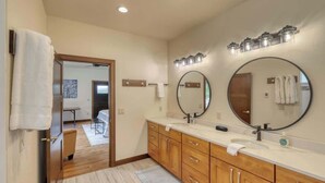 A modern bathroom with wooden cabinets, a double sink, and a large mirror.
