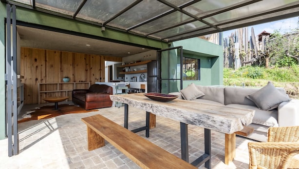 Un espacio de sala-comedor abierto con suelo de madera, una mesa de comedor, un sofá y un banco.