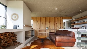 Una sala de estar moderna con un sofá de cuero, una mesa redonda de madera y un tapiz de cuero de vaca.