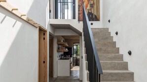 Un interior moderno con una escalera, un banco de madera y vistas al área de la cocina.