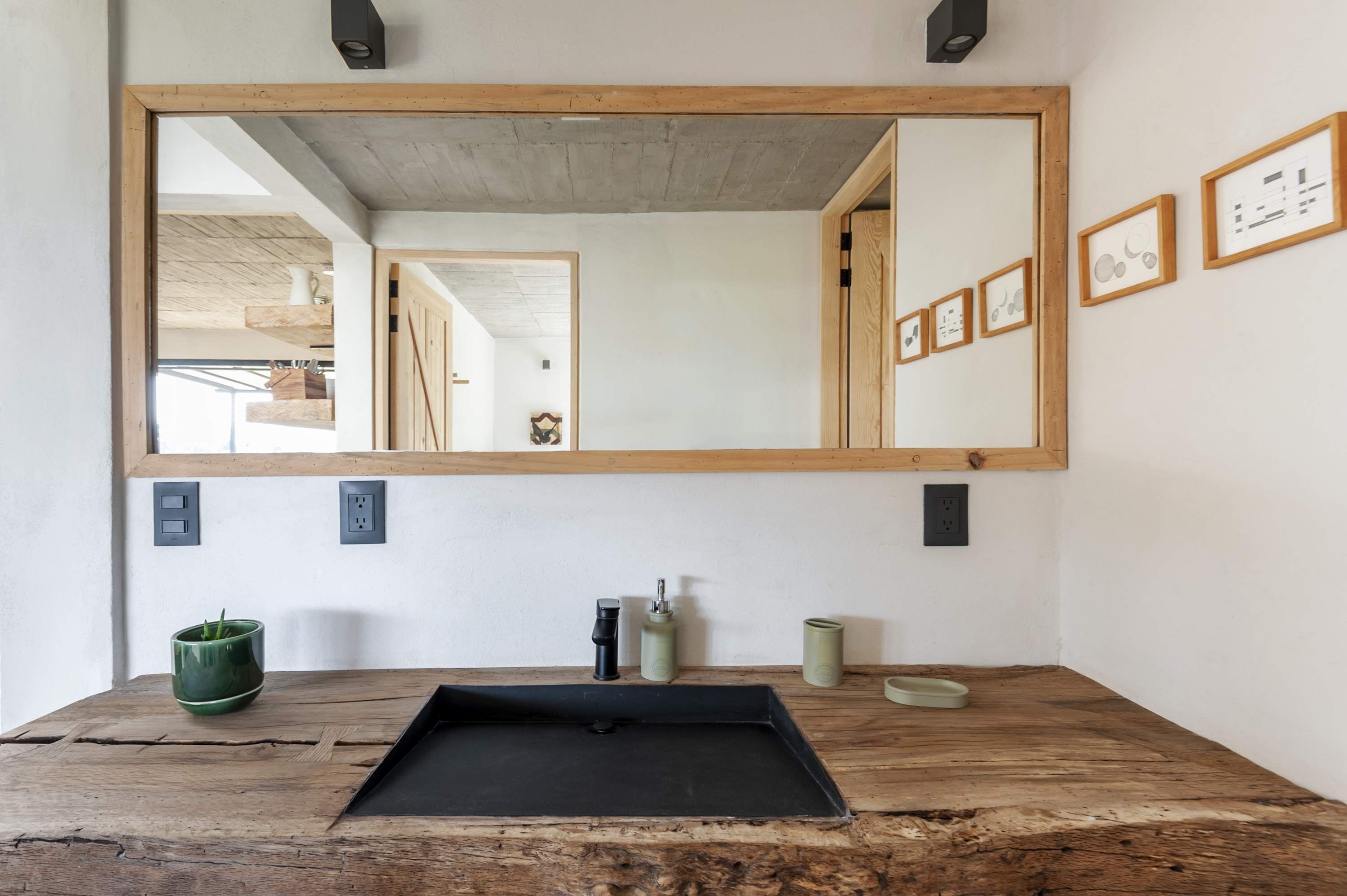 Une salle de bain avec un meuble-lavabo en bois, un lavabo noir et un grand miroir.