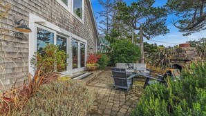 Et hus med facade i mursten, en terrasse med grill og siddepladser samt en pejs i sten.