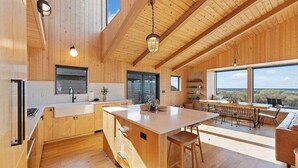 Una cocina amplia con alacenas de madera, una isla grande y un comedor con vistas.