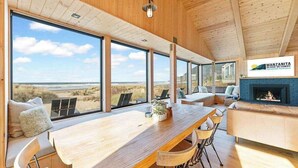 Un interior moderno con una gran mesa de madera para comer, asientos y una chimenea.