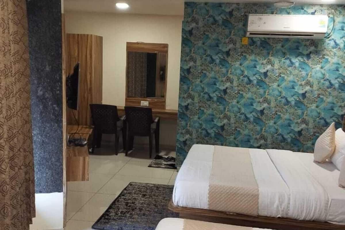 Hotellihuone, jossa on kaksi sänkyä, työpöytä, tuoli ja peili.