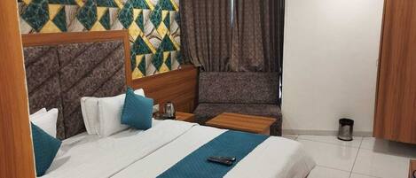 Una habitación de hotel con cama, sofá, una mesita y un armario.