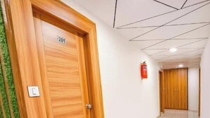 Passadís amb una porta de fusta amb la inscripció '201', un extintor a la paret i un sòl de rajoles.