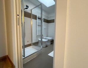 Un baño moderno con cabina de ducha de vidrio, inodoro y bidé.