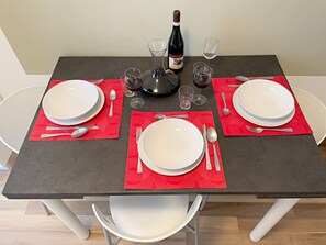 Una mesa puesta con platos, cubiertos, copas y una botella de vino.