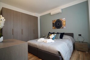 Un dormitorio con una cama, un armario, una mesita de noche y un aire acondicionado instalado en la pared.