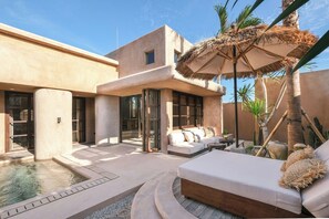 A modern outdoor living area with a pool, lounge chairs, and a thatched umbrella. - Pulau Alam at Bocoa Villas (Canggu)