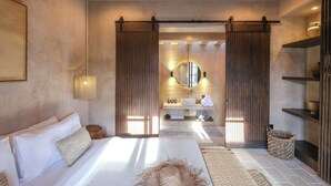A modern bedroom with a large bed, a bedside table, a mirror, a wooden shelf, and a hanging light fixture. - Pulau Alam at Bocoa Villas (Canggu)