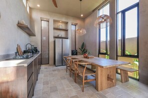 A modern kitchen with a wooden island, built-in appliances, and large windows. - Pulau Alam at Bocoa Villas (Canggu)