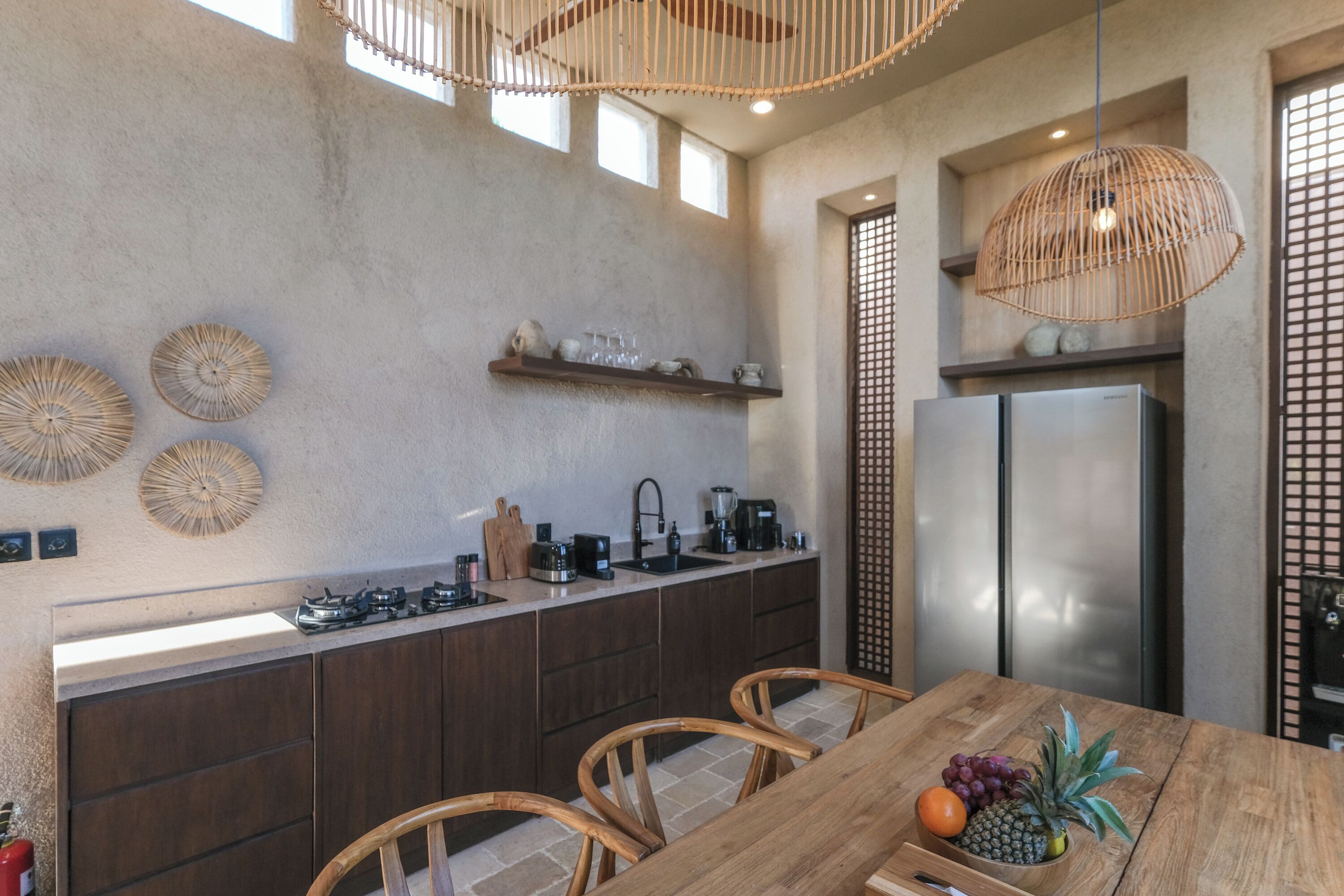 Una cocina moderna con una isla central, electrodomésticos de acero inoxidable y un comedor con sillas de madera.