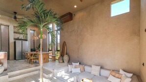 A spacious living area with a large sectional sofa, a dining table, and a tall palm tree. - Pulau Alam at Bocoa Villas (Canggu)