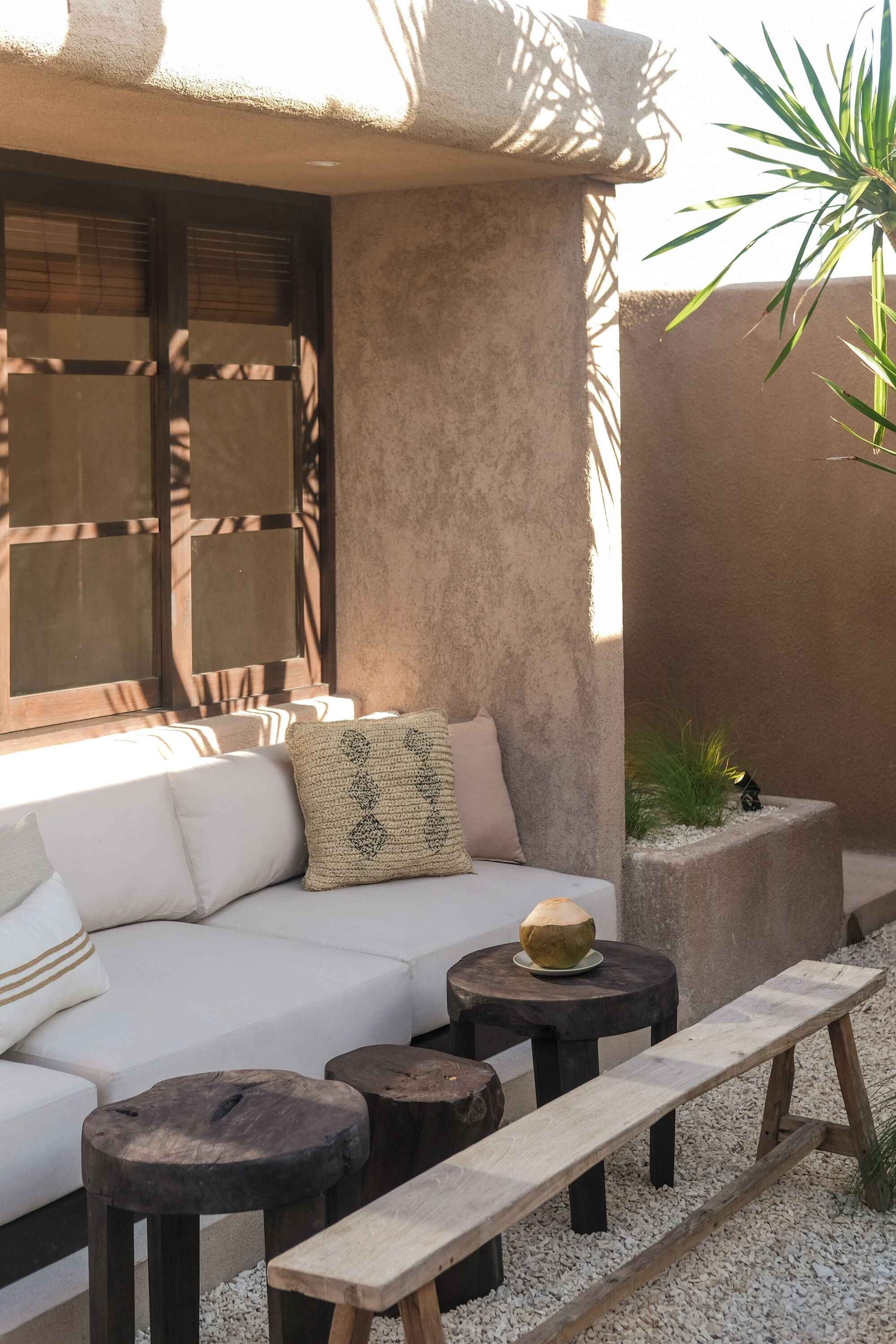 An outdoor seating area with a sofa, two round tables, and a bench.