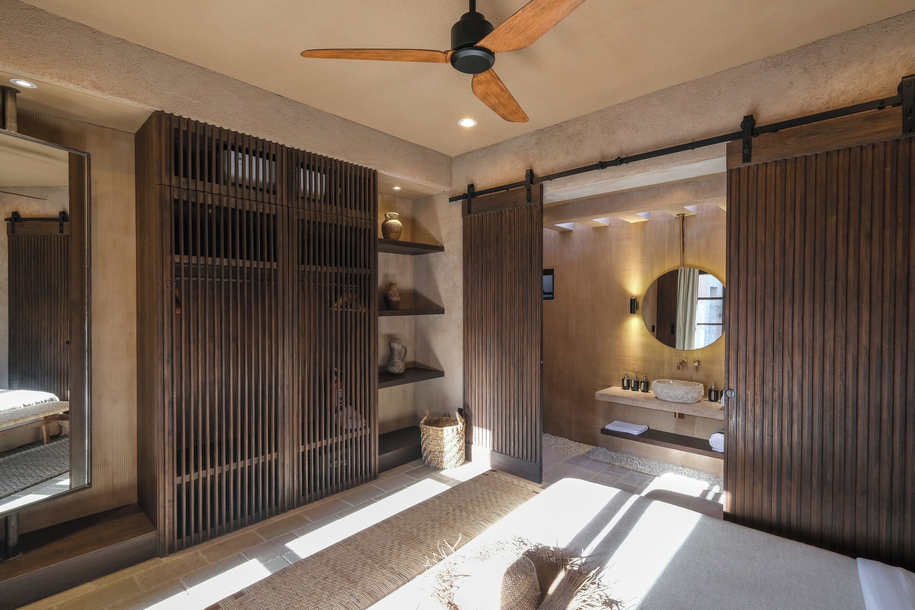 A modern bathroom with a large mirror, wooden paneling, and a ceiling fan.