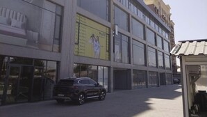 En bygning med flere etager, store vinduer og en central gul reklame.