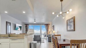 Una cocina amplia con comedor, un televisor montado en la pared y vistas al exterior.