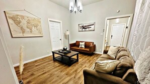 Een woonkamer met een bruine leren bank, een salontafel, een wereldkaart aan de muur en een wereldbol op de tafel.