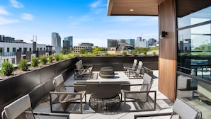 Terraza en la azotea con mobiliario exterior, vistas de la ciudad y un estilo arquitectónico moderno.